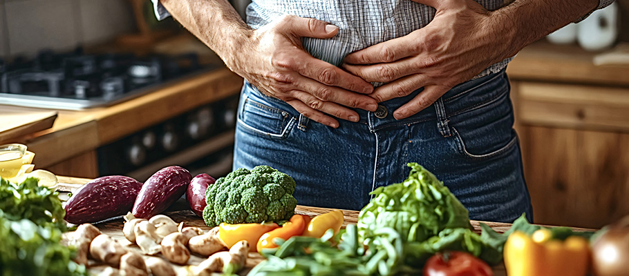 Hombre-se-sostiene-el-vientre-con-una-expresión-dolorosa-en-su-cocina